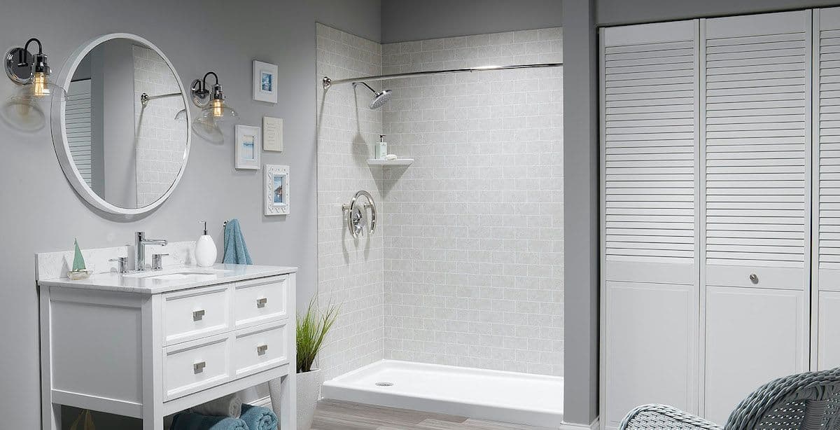A light gray bathroom with a walk-in shower with light-gray tile-patterned walls.